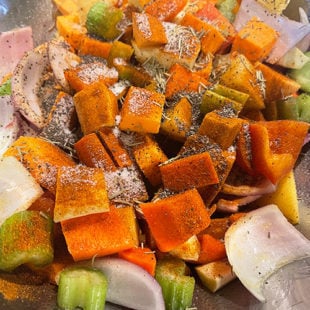 chopped veggies tossed with dried herbs, oil in a bowl