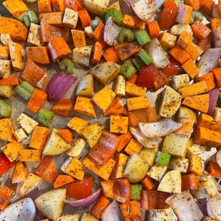 veggies tossed in herbs and oil placed on a baking tray