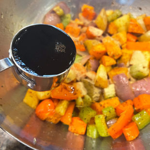 balsamic vinegar being added to a bowl of veggies