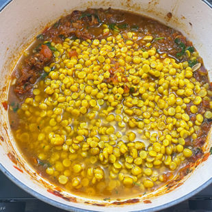 boiled chana dal being added to a pot
