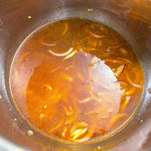 water being added to a pot with soy sauce, onions
