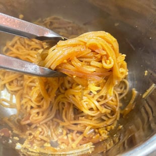 pair of tongs holding noodles