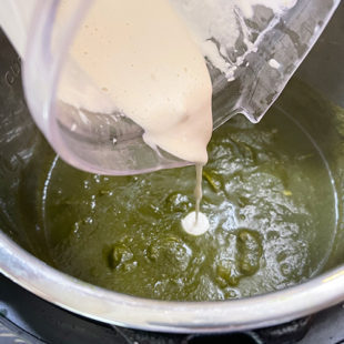 cashew cream being added to spinach puree