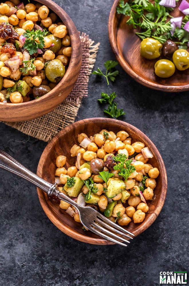 chickpea salad served in a 2 wooden plates and 1 wooden bowl