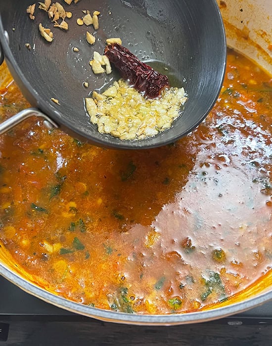 adding garlic tadka to a pot of dal