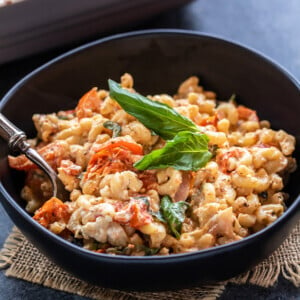 pasta served in a black bowl, garnished with basil