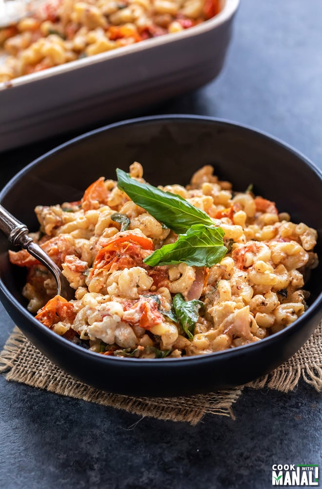 pasta served in a black bowl, garnished with basil