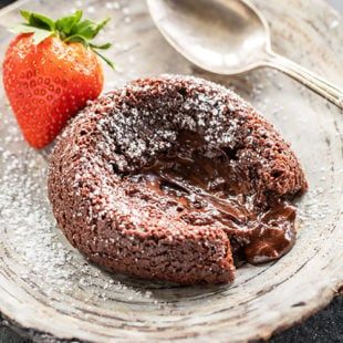 chocolate lava cake placed on a plate with melted chocolate oozing from the center