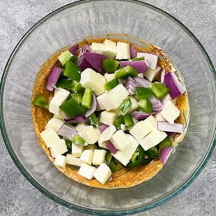 paneer, onion and peppers being added to a bowl with yogurt and spices