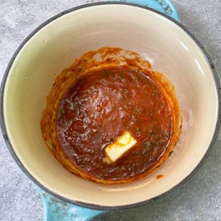 pat of butter in a pan filled with tomato sauce