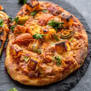 baked naan pizza placed on a black board