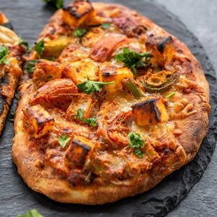 baked naan pizza placed on a black board