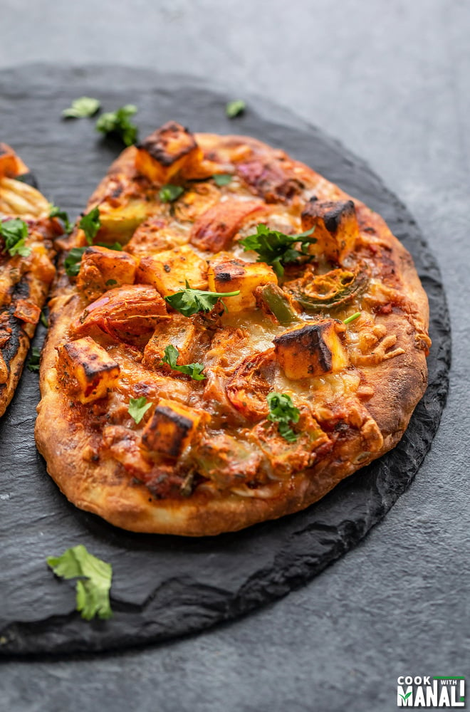 paneer tikka naan pizza placed on a black board