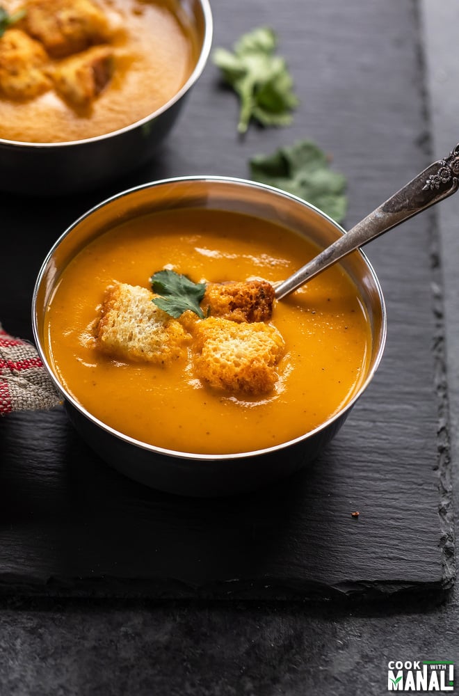 bowl of tomato soup topped with croutons and cilantro