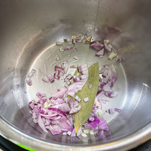 chopped onions, bay leaf in a steel pot
