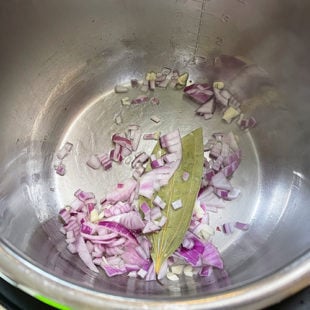 chopped onions, bay leaf in a steel pot