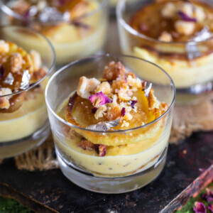 small dessert glasses filled with rabdi, malpua and garnished with dried rose petals