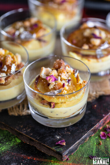 small dessert glasses filled with rabdi, malpua and garnished with dried rose petals