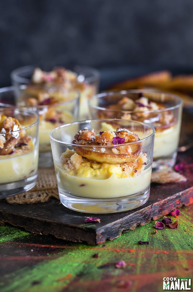 small dessert glasses filled with rabdi, malpua and garnished with dried rose petals