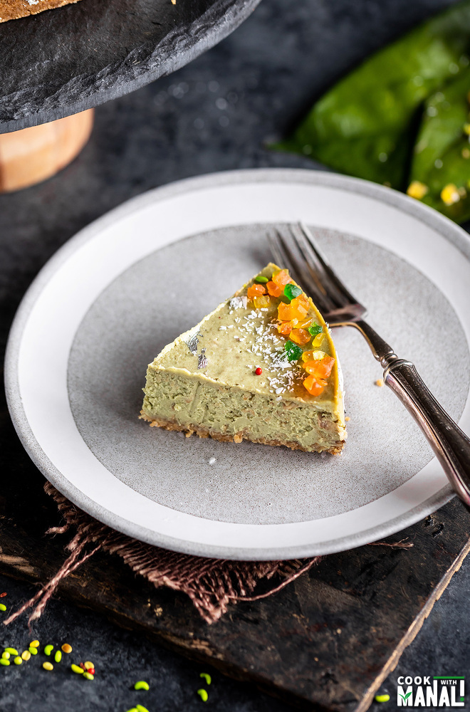 slice of green color cheesecake on a white plate with a fork placed on the side