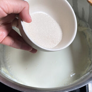 sugar being added to a pot of milk