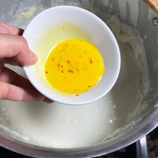 saffron milk being added to a pot of milk