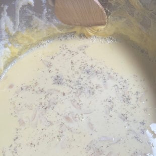 spatula scraping the sides of a pot with milk