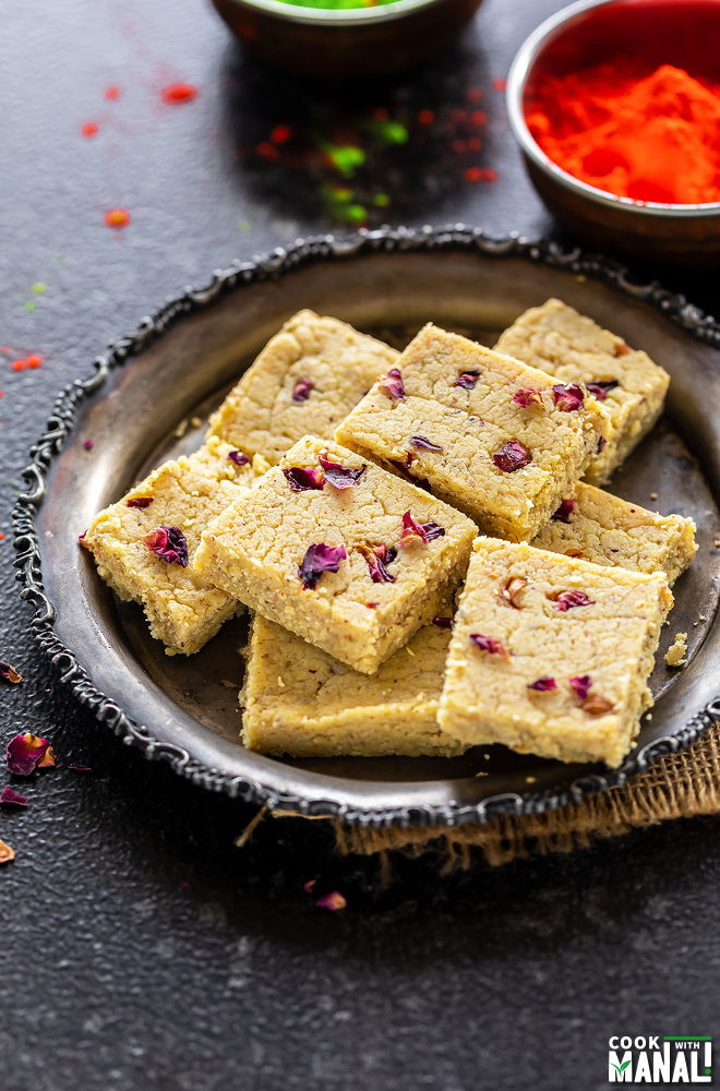 plate of thandai burfi with holi colors in the background