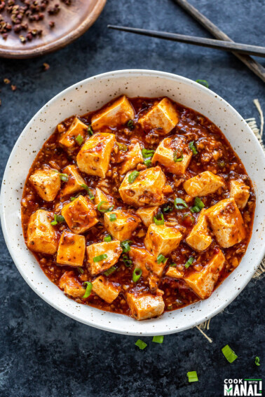 mapo tofu served in a white bowl and garnished with green onions