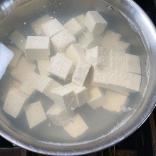 tofu submerged in hot water in a pan