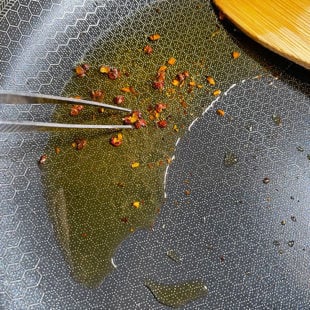 sichuan peppercorns in oil being picked by tweezer