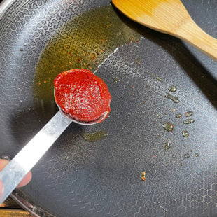 chili paste being added to a pan