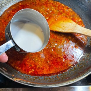 cornstarch slurry being added to a pan