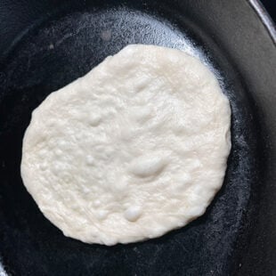 rolled naan placed on skillet