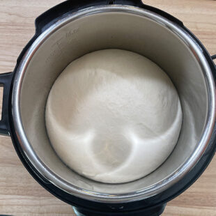risen dough in a steel bowl