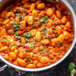 gnocchi in tomato sauce in a steel pan garnished with cilantro