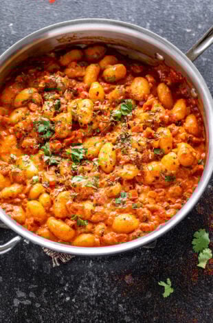 gnocchi in tomato sauce in a steel pan garnished with cilantro