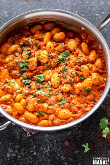 gnocchi in tomato sauce in a steel pan garnished with cilantro