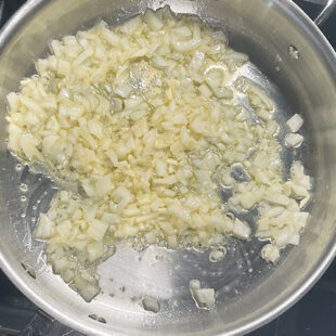 chopped onion and garlic being cooked in oil in a pan