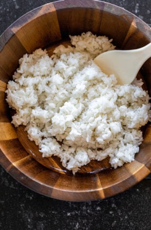 white rice in a wooden bowl with a rice paddle