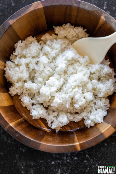 white rice in a wooden bowl with a rice paddle