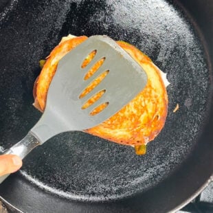 sandwich being pressed with a spatula on a pan