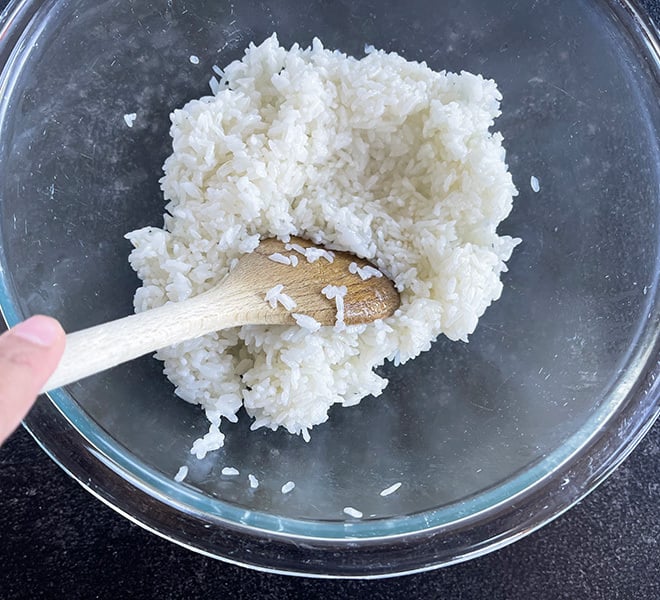 sticky rice in a glass bowl with a wooden spatula