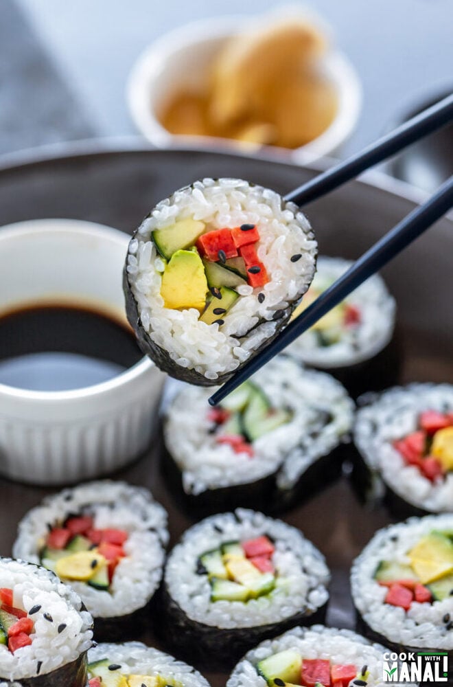 pair of chopstick holding a vegan sushi roll