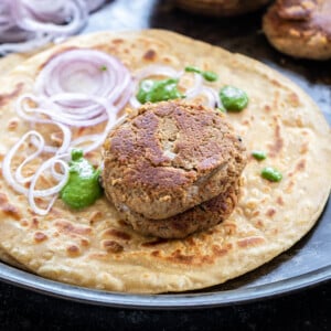 two patties placed on a paratha along with chutney and sliced onion