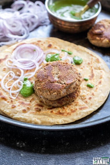 two patties placed on a paratha along with chutney and sliced onion
