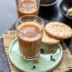 glass filled with chai and 2 cookies placed on the side