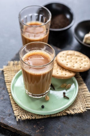 glass filled with chai and 2 cookies placed on the side