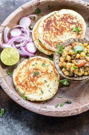 bread kulcha served with a bowl of matar chaat, sliced onion and a round of lemon in a pattal