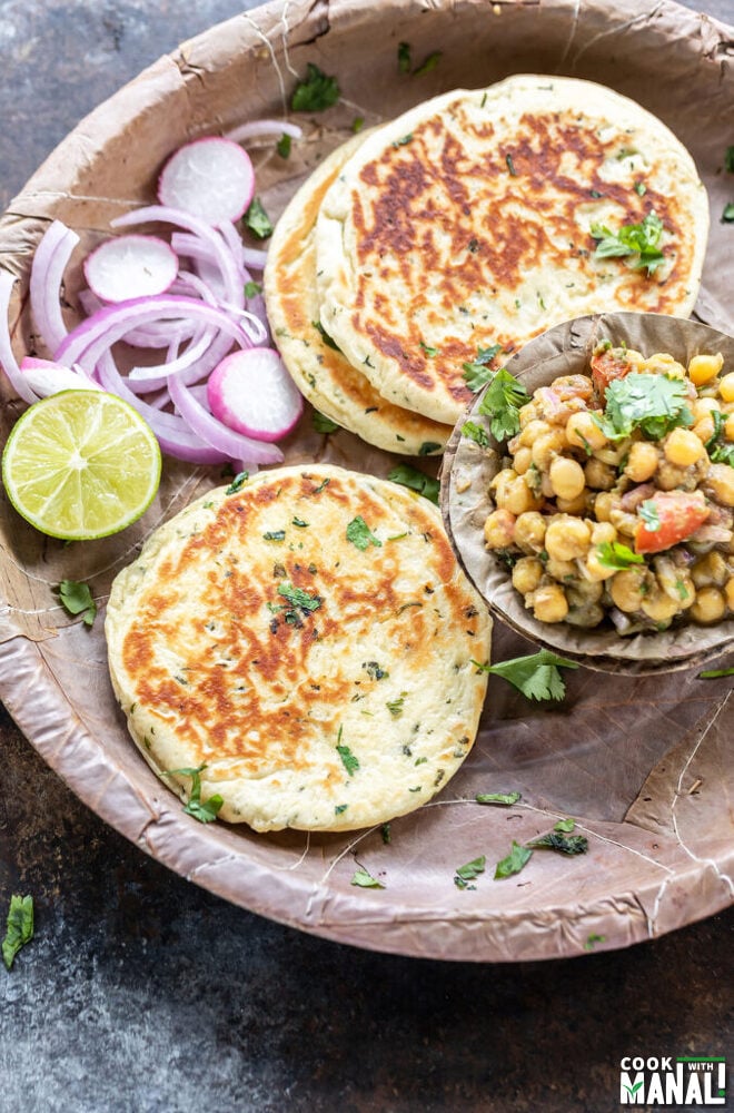 bread kulcha served with a bowl of matar chaat, sliced onion and a round of lemon in a pattal